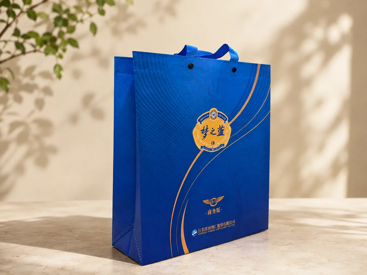 Laminated non-woven carrier bag in blue and gold with reinforced webbing handles, press studs and a gusseted base
